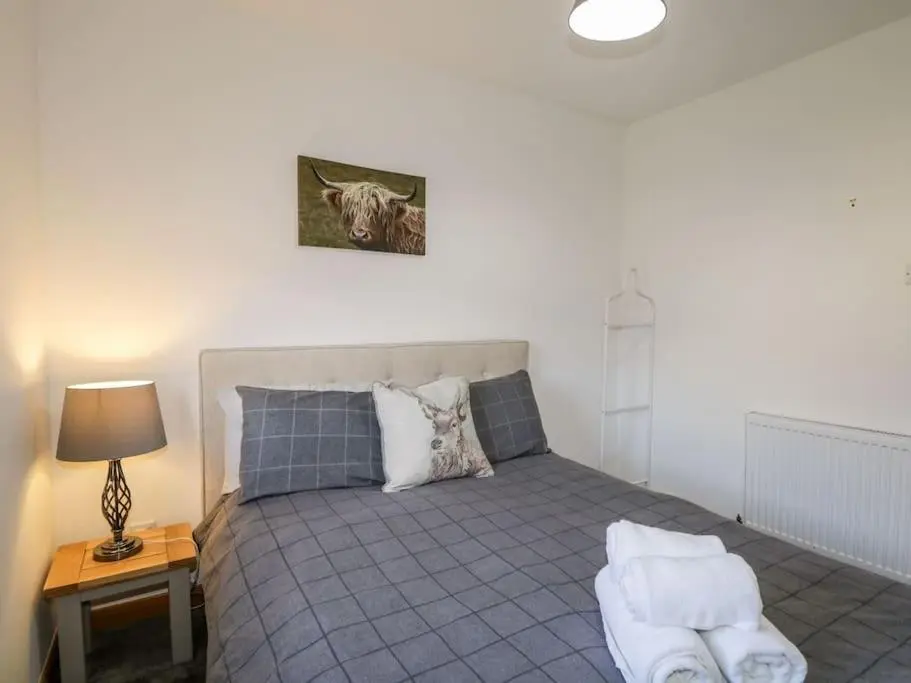 a bedroom with a bed and a table with a lamp at Stewart's Cottage, Aviemore Centre in Aviemore