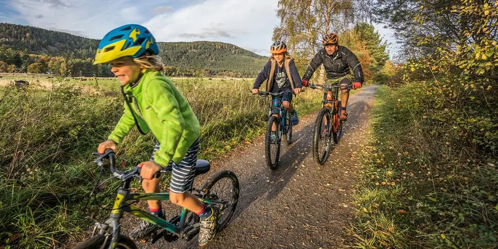 three people riding bikes down a dirt road at Stewart's Cottage, Aviemore Centre in Aviemore