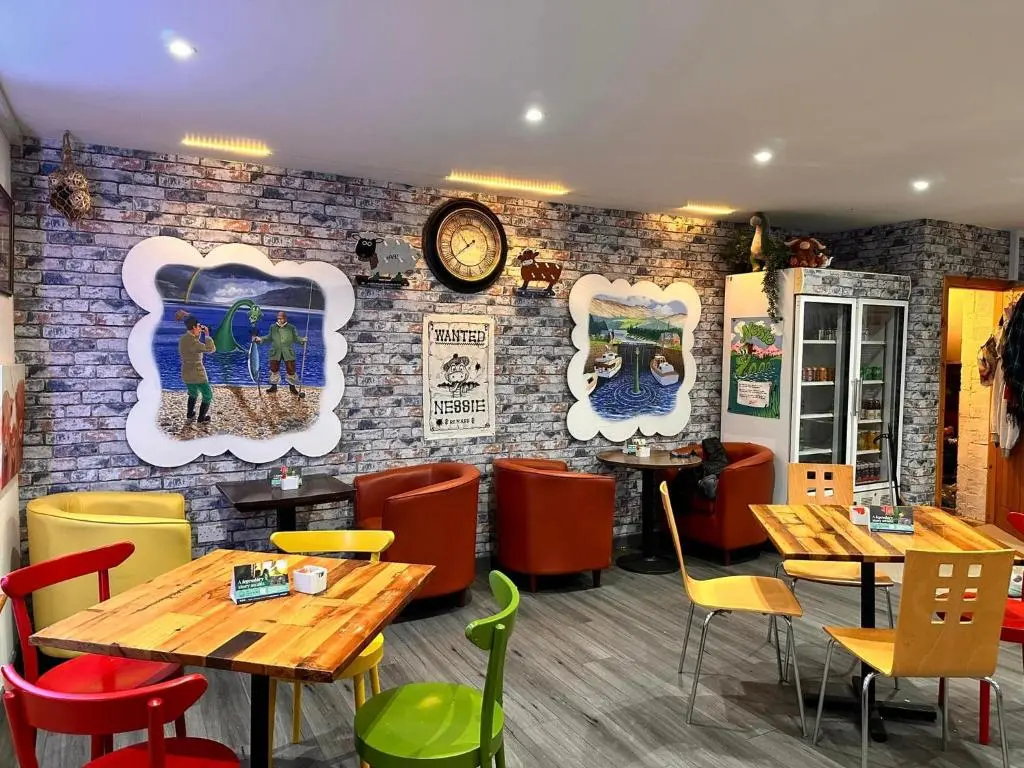 a restaurant with wooden tables and colorful chairs at Loch Ness Gate House in Fort Augustus