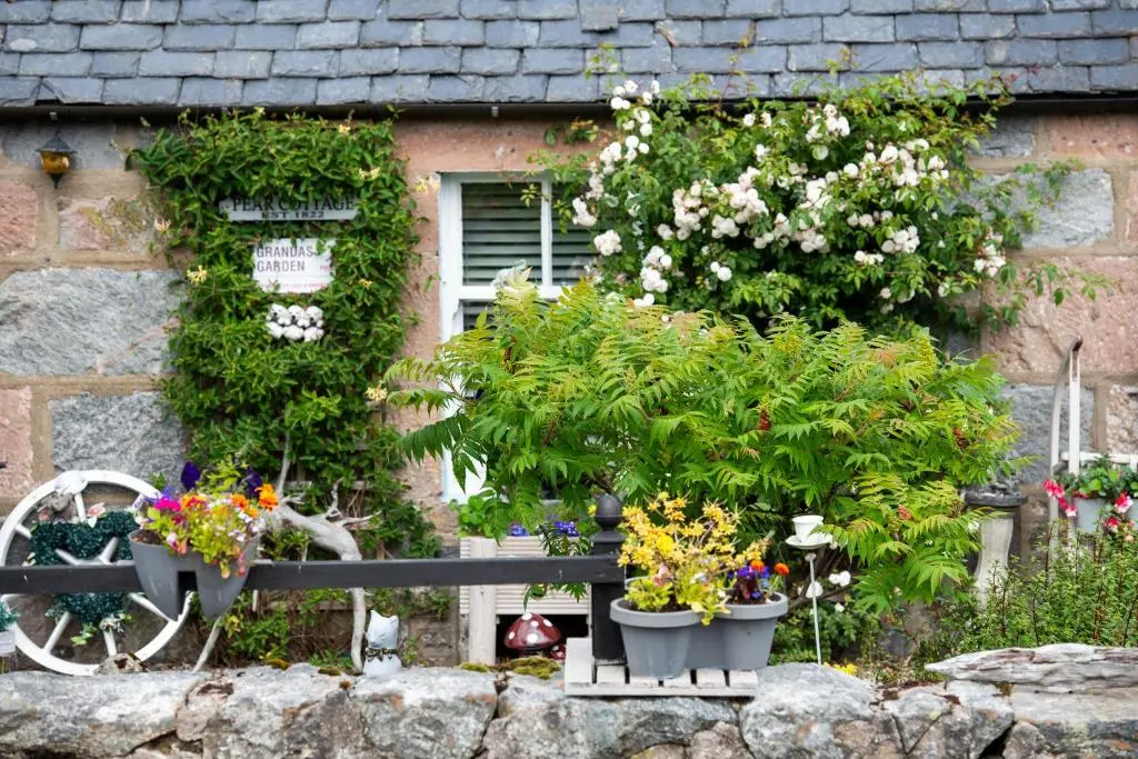 a bench with flowers and plants in front of a building at Loch Ness Gate House in Fort Augustus