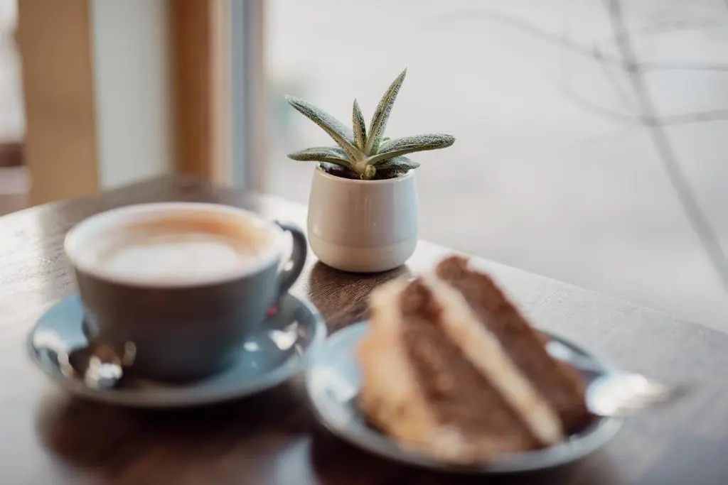 a cup of coffee and a piece of cake on a table at Loch Ness Gate House in Fort Augustus