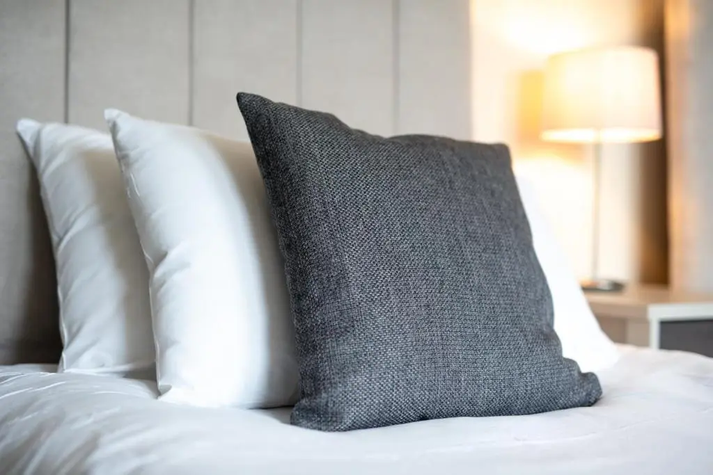 a black pillow on a bed with white pillows at Loch Ness Gate House in Fort Augustus