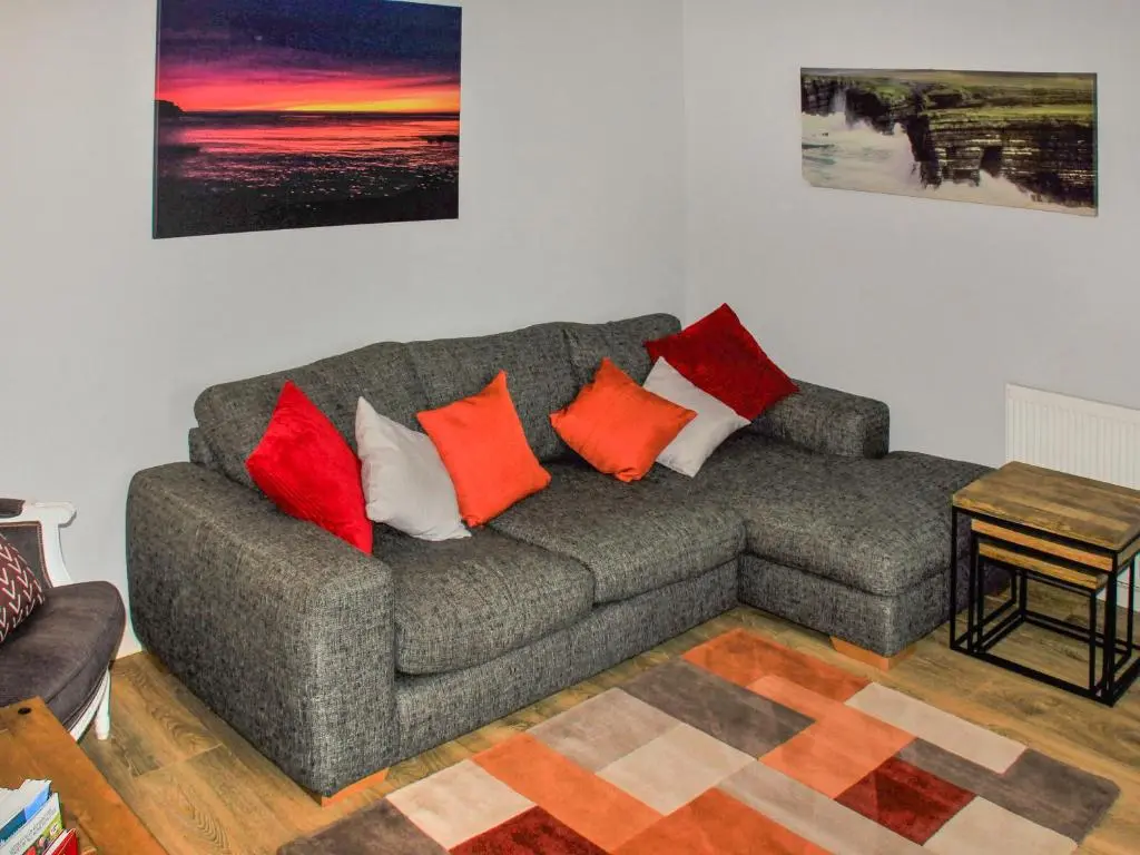 a living room with a gray couch with colorful pillows at Harbour Road in Gardenstown