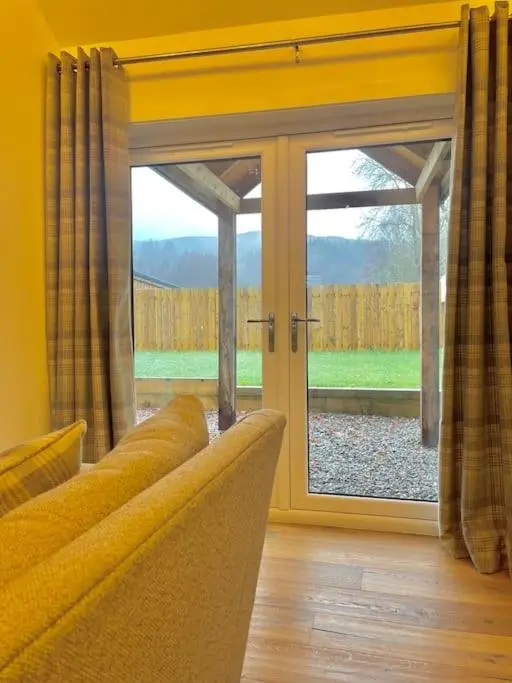 a living room with a couch and a sliding glass door at The Old Croft in Fort Augustus