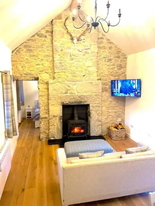 a living room with a stone fireplace and a couch at The Old Croft in Fort Augustus