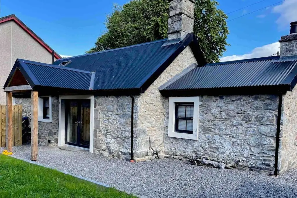 a stone house with solar panels on it at The Old Croft in Fort Augustus