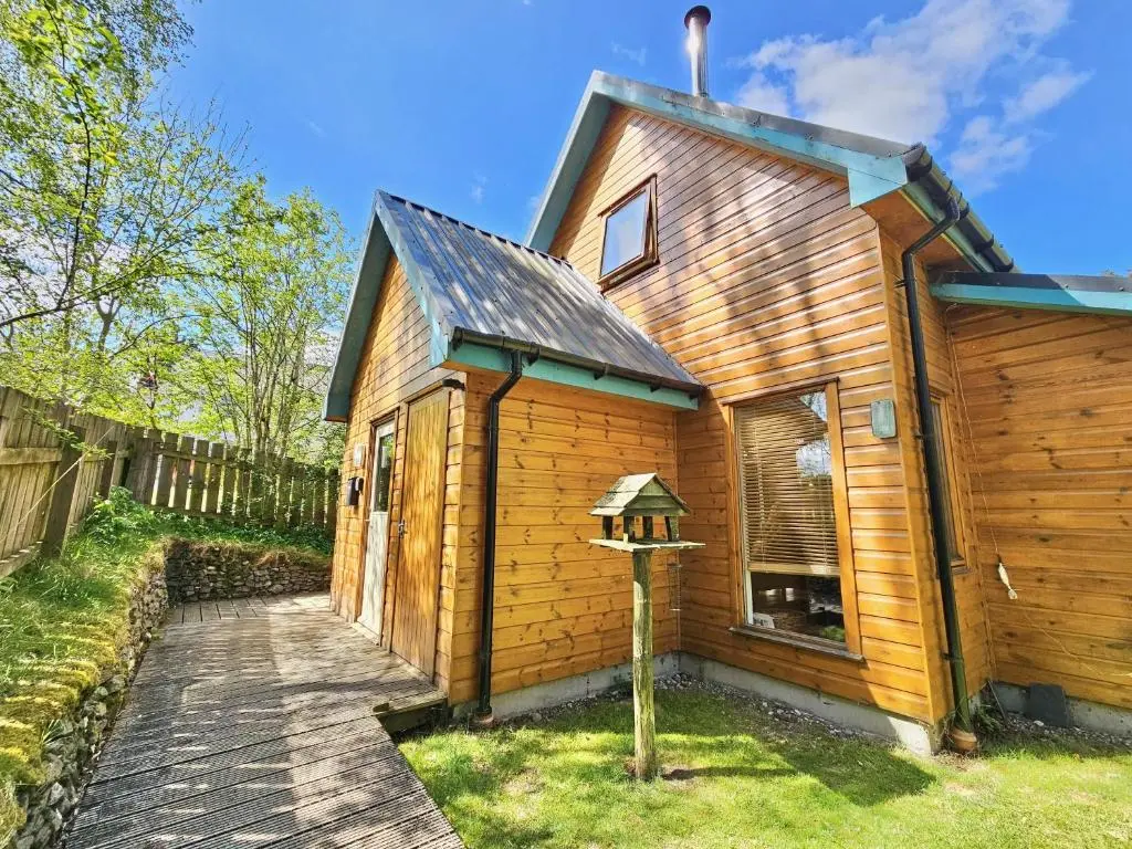 a wooden house with a bird feeder in front of it at Baltinna East - by Where Stags Roar in Newtonmore