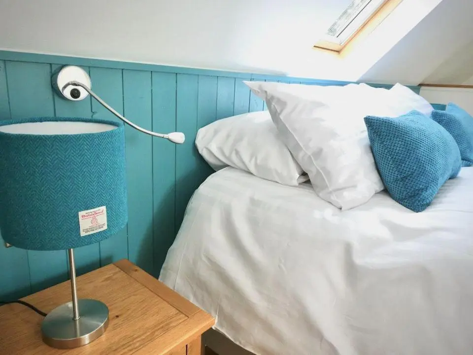 a bedroom with a bed and a table with a lamp at Baltinna West - by Where Stags Roar in Newtonmore