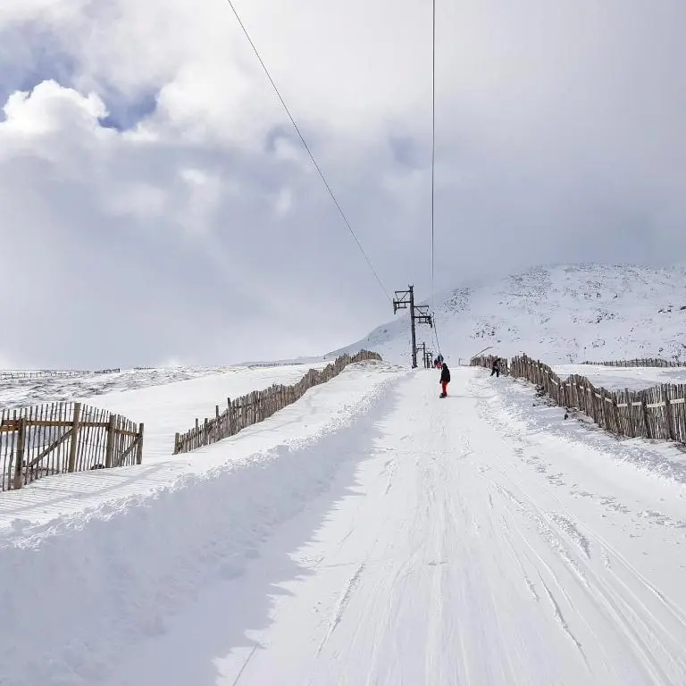a person riding a ski lift in the snow at The Byre - by Where Stags Roar in Newtonmore