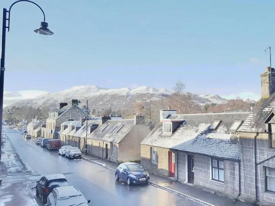 a snow covered street in a town with cars parked at Caman House Apt 2 - by Where Stags Roar in Newtonmore