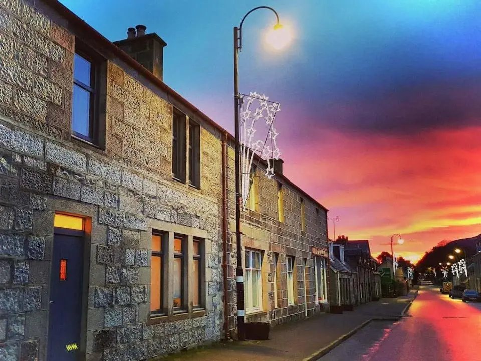 a street light next to a building with a sunset at Caman House Apt 2 - by Where Stags Roar in Newtonmore