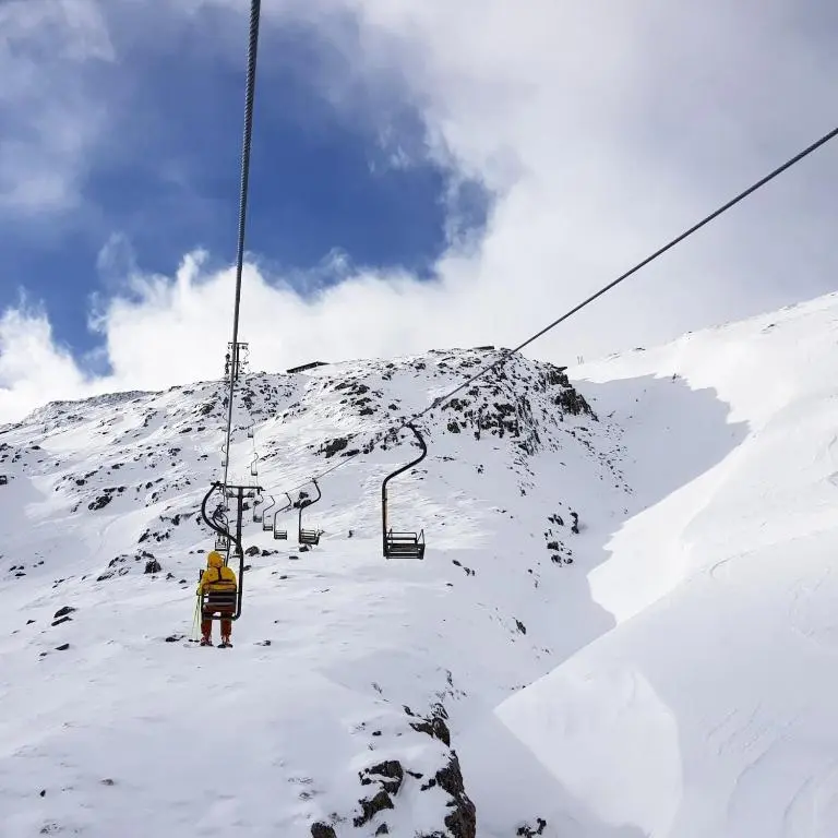 a person on a ski lift on a snow covered mountain at Caman House Apt 2 - by Where Stags Roar in Newtonmore