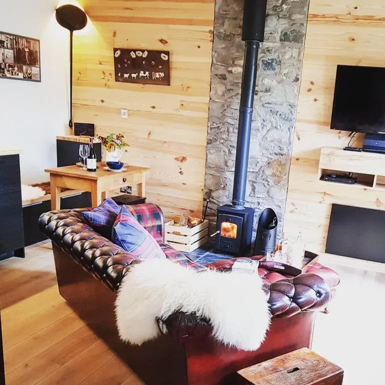 a living room with a leather couch with a stove at The Bakehouse - by Where Stags Roar in Newtonmore