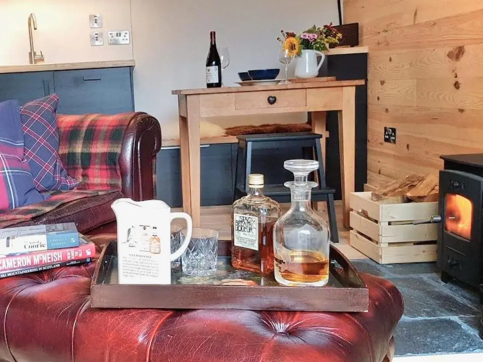 a tray with two bottles of whiskey on a couch at The Bakehouse - by Where Stags Roar in Newtonmore