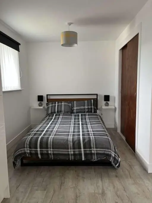 a bedroom with a bed with a plaid blanket at Lovely one bed, open plan studio apartment. in Culloden