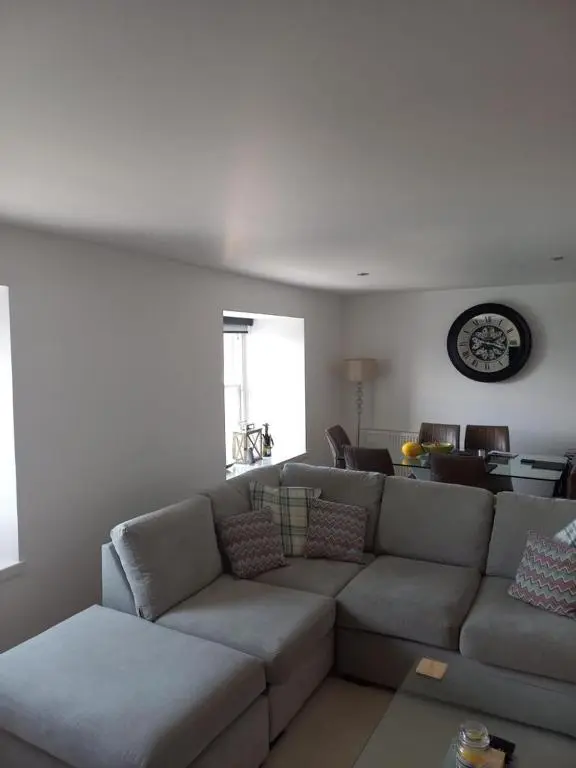 a living room with a couch and a clock on the wall at Telford Escape in Elgin