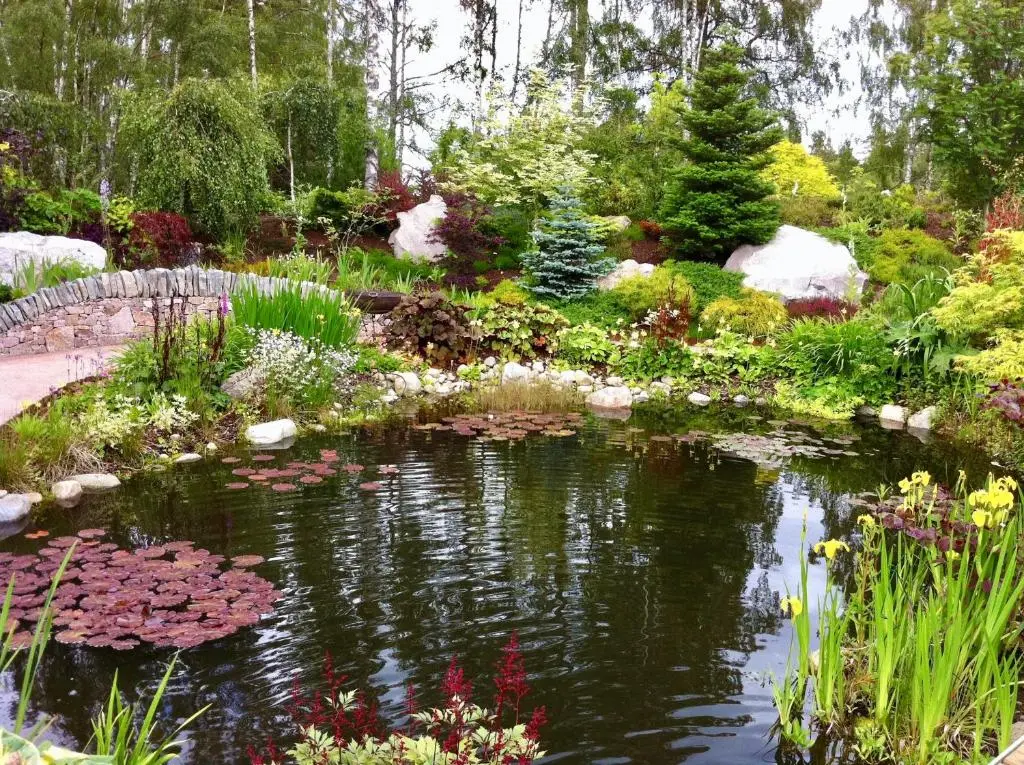 a pond in a garden with flowers and a bridge at The Polchar - Aviemore in Aviemore