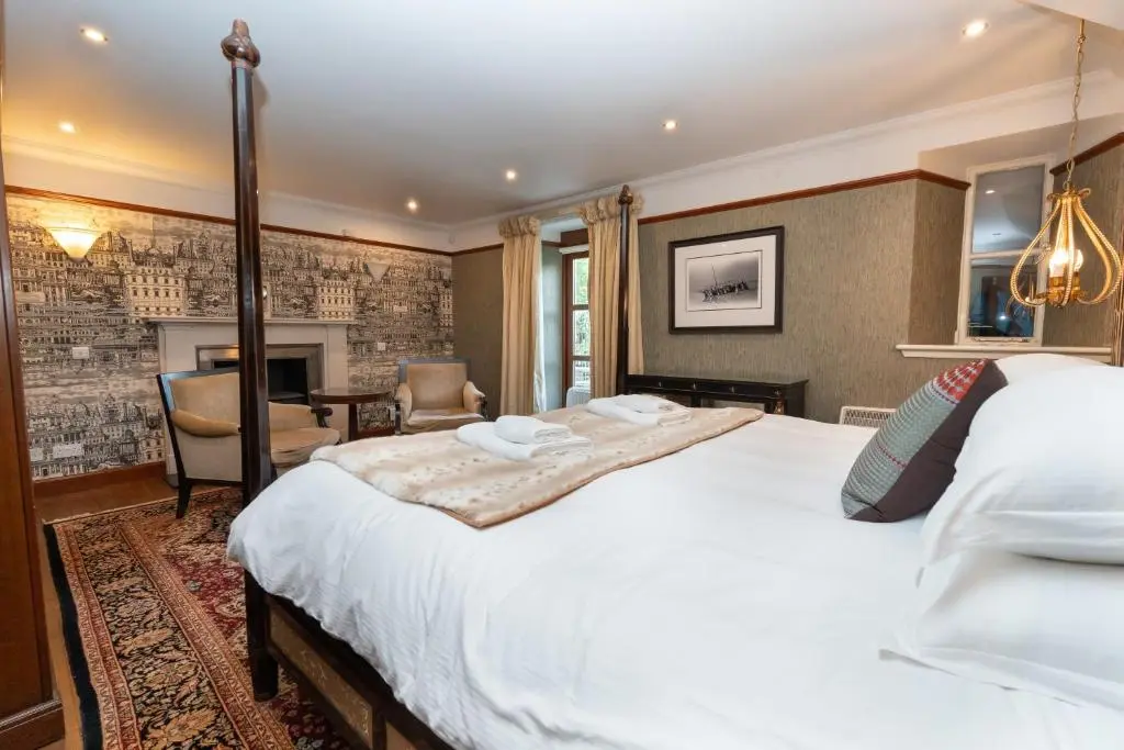a bedroom with a large white bed and a fireplace at The Polchar - Aviemore in Aviemore