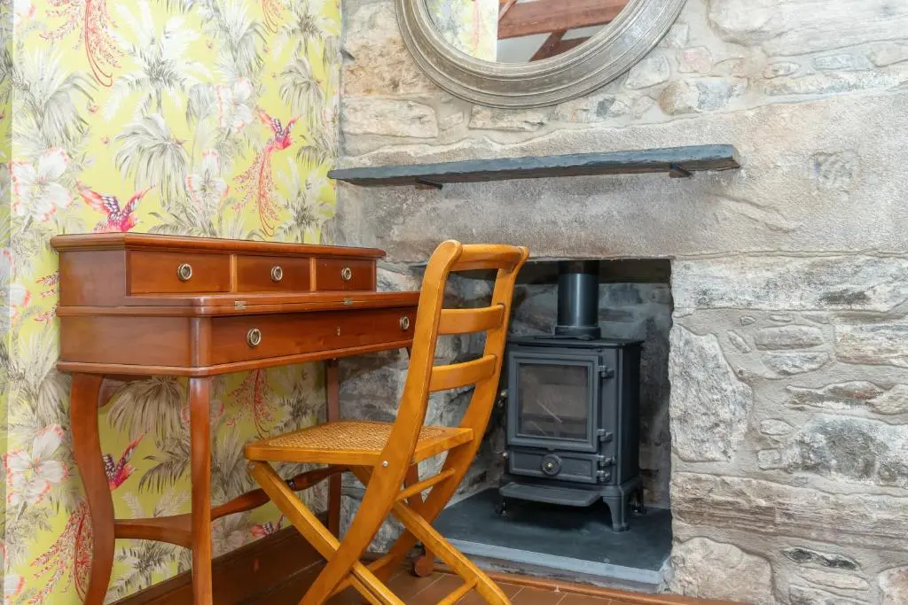 a desk with a chair and a wood stove at The Polchar - Aviemore in Aviemore