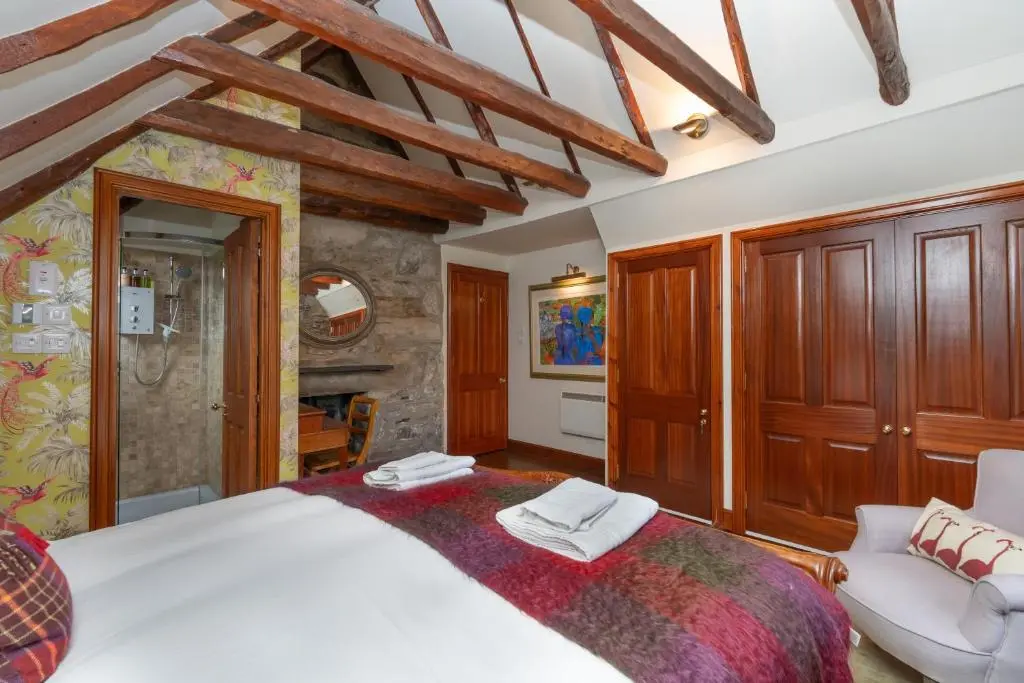 a bedroom with a large bed and a chair at The Polchar - Aviemore in Aviemore