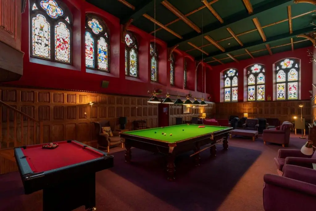 a room with a pool table and stained glass windows at Cloister View in Fort Augustus