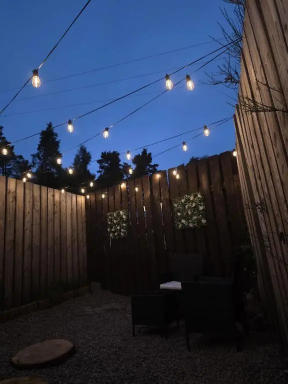 a fence with string lights and a fence with chairs at Kaoglen Warren - Pet friendly - Hot Tub - Cairngorms in Blairgowrie