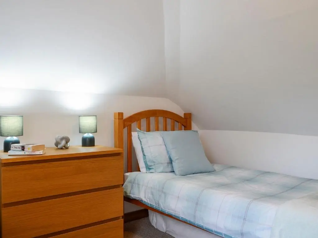 a bedroom with a bed and a dresser with a night stand at Old Mill Cottage in Blair Atholl