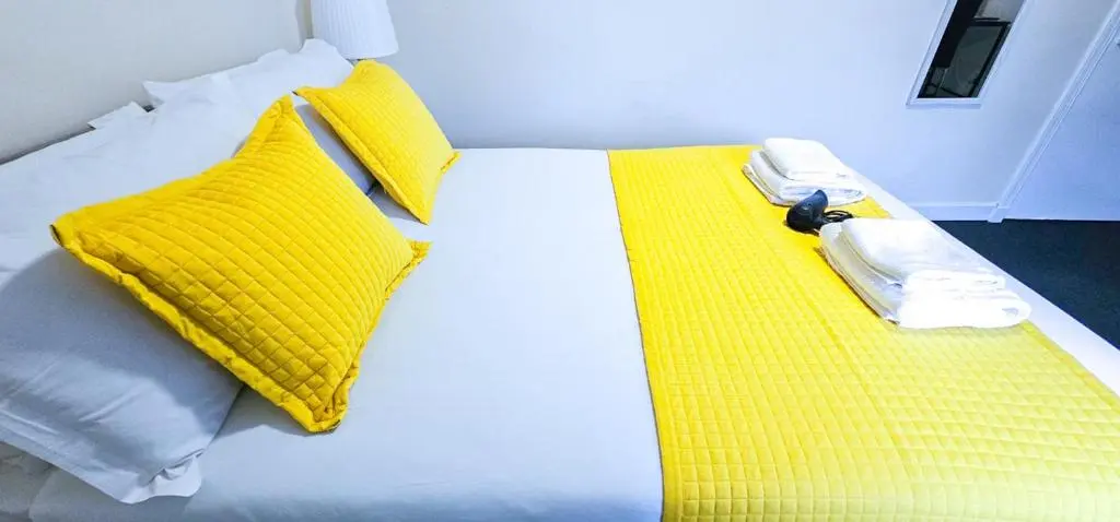a bed with yellow pillows and a phone on it at mySTAYINN Telford 7 Bedroom House in Inverness