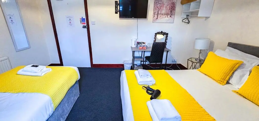 two beds in a room with yellow and white sheets at mySTAYINN Telford 7 Bedroom House in Inverness