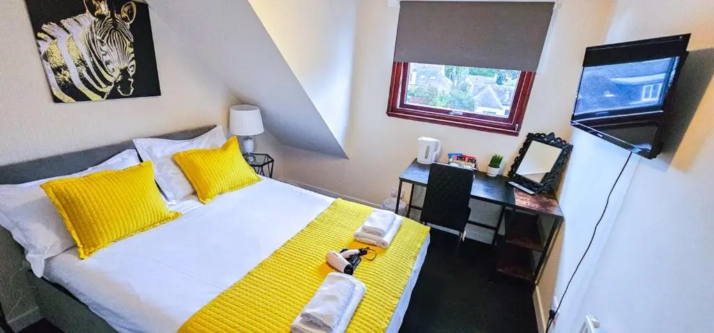 a bedroom with a bed with yellow pillows and a desk at mySTAYINN Telford 7 Bedroom House in Inverness