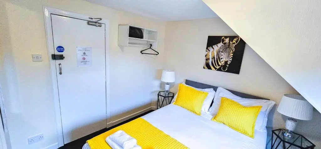 a bedroom with a bed with yellow and white pillows at mySTAYINN Telford 7 Bedroom House in Inverness