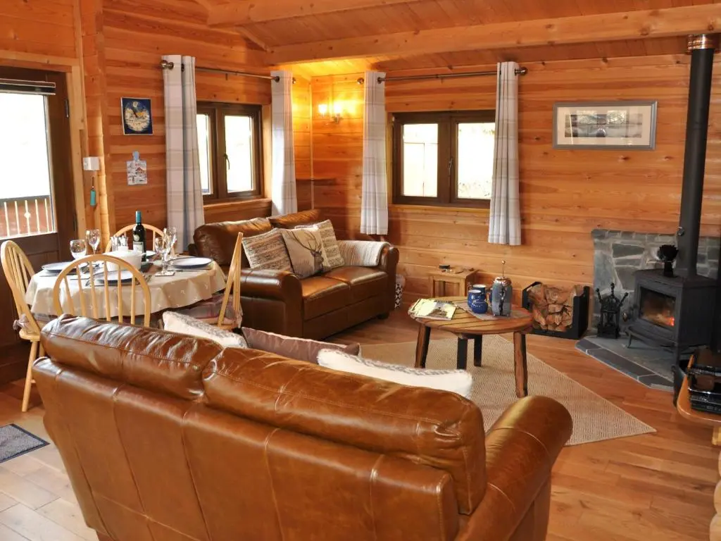 a living room with leather furniture and a fireplace at Cairnhill Lodge - Award-Winning Luxury Highland Retreat in Blairgowrie