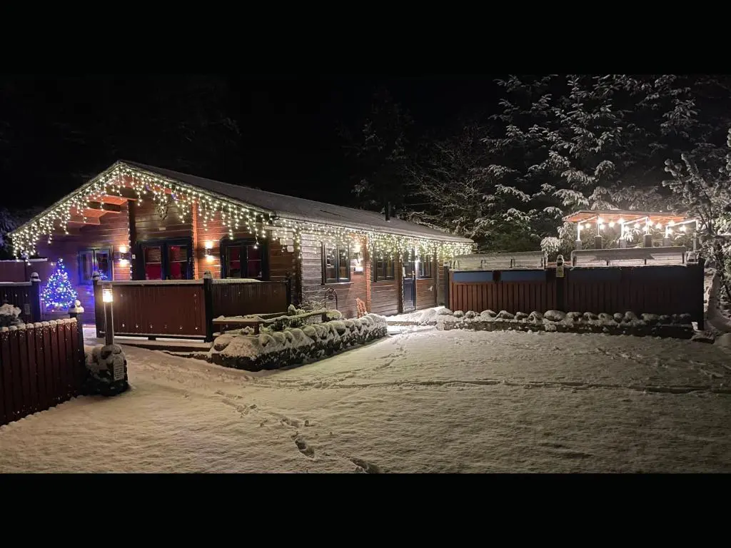 a house covered in christmas lights in the snow at Cairnhill Lodge - Award-Winning Luxury Highland Retreat in Blairgowrie