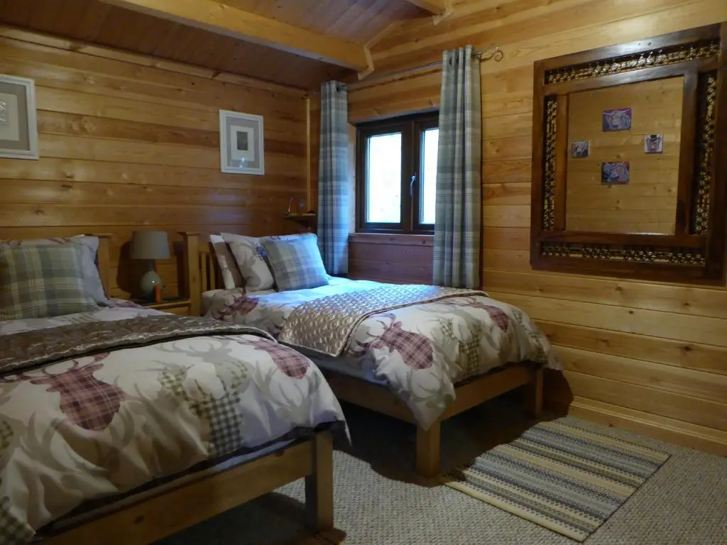 a bedroom with two beds in a log cabin at Cairnhill Lodge - Award-Winning Luxury Highland Retreat in Blairgowrie