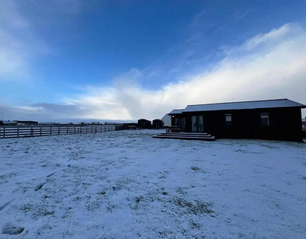 a building in a field with snow on the ground at Farr North Lodge 1 By The Sea in Wick