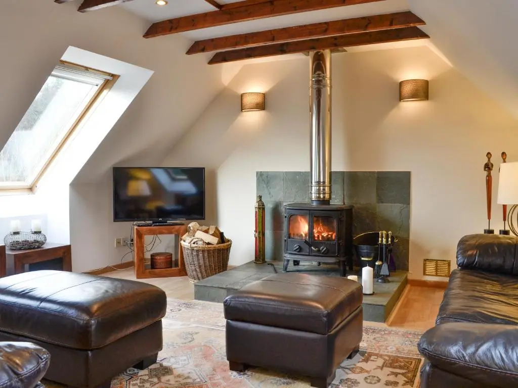 a living room with a fireplace and leather furniture at Dee Valley View in Aboyne