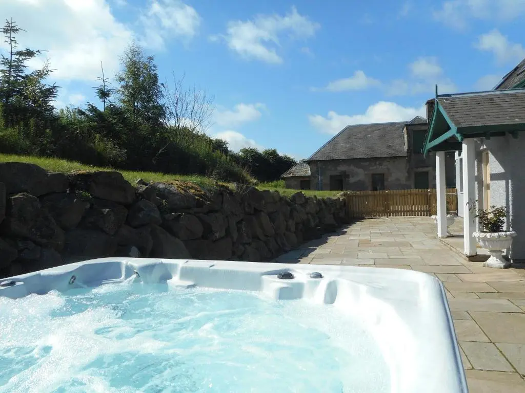 a hot tub in a yard with a stone wall at Rose Cottage with Hot Tub in Cray