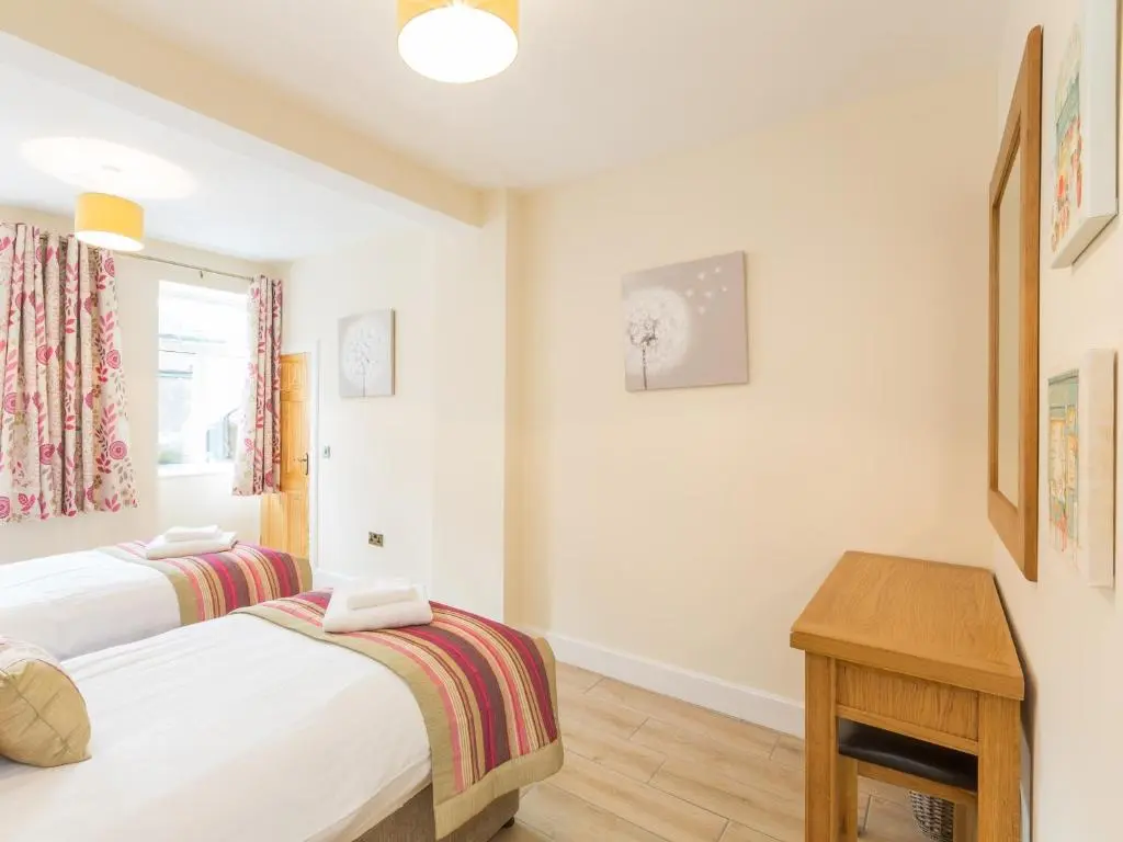 a bedroom with two beds and a table and a window at Rose Cottage with Hot Tub in Cray