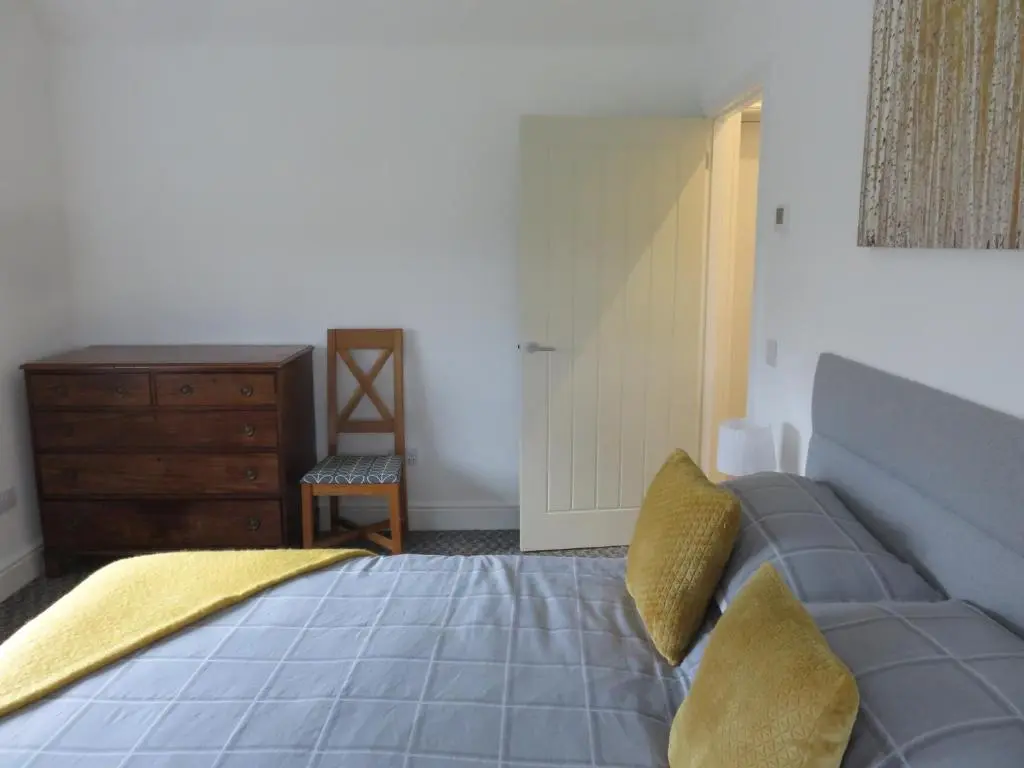 a bedroom with a bed with yellow pillows and a dresser at Old Schoolhouse in Lairg