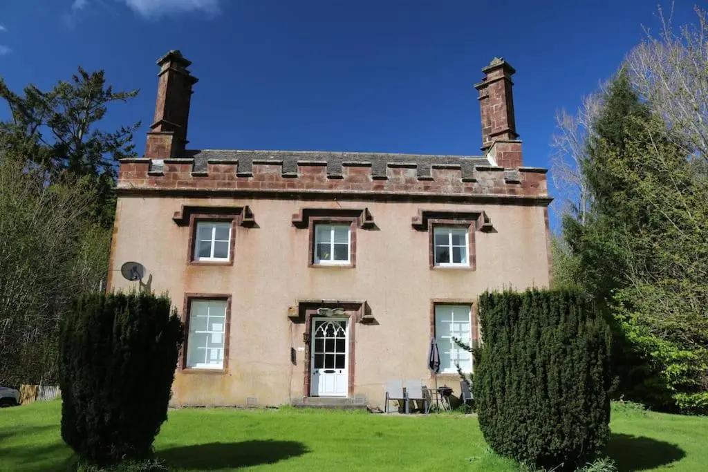 an old house with two chimneys on a green lawn at Oldwood. Fyvie. in Turriff