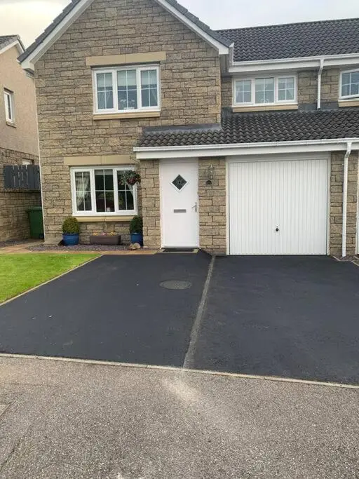a house with two garage doors and a driveway at Three bedroom house in Culloden, Inverness in Culloden
