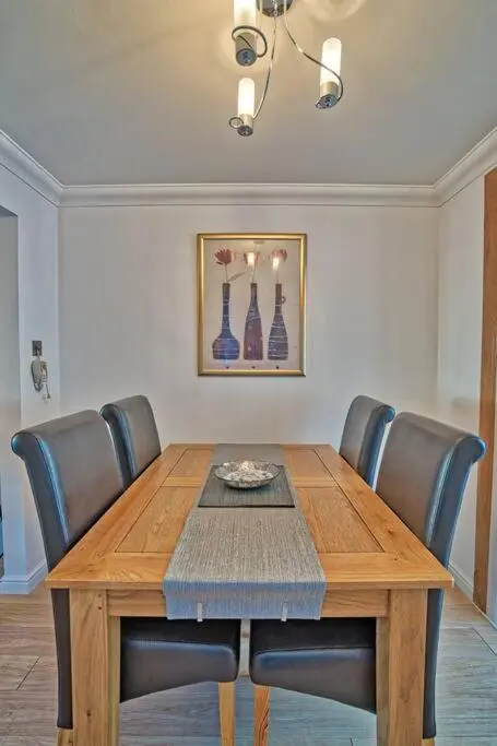 a dining room table with leather chairs and a wooden table at Three bedroom house in Culloden, Inverness in Culloden