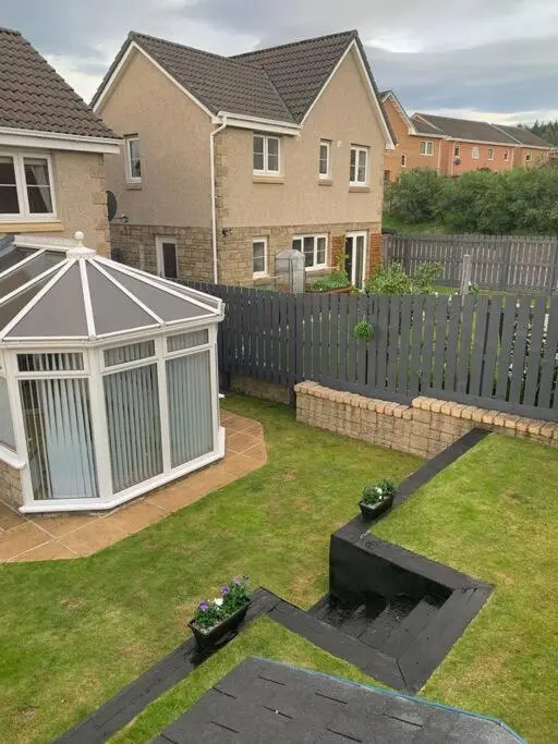 a backyard with a fence and a garden with a gazebo at Three bedroom house in Culloden, Inverness in Culloden