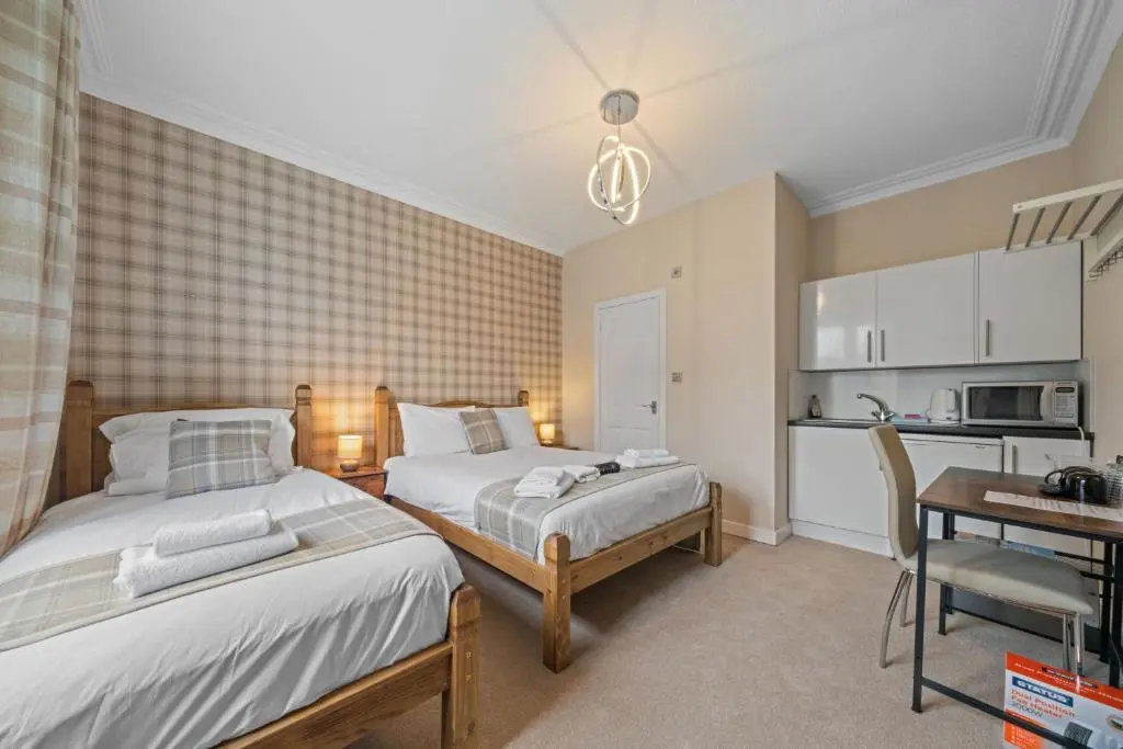 a bedroom with two beds and a table and a kitchen at mySTAYINN Strathblane 7 Bedroom Full House - Inverness in Inverness