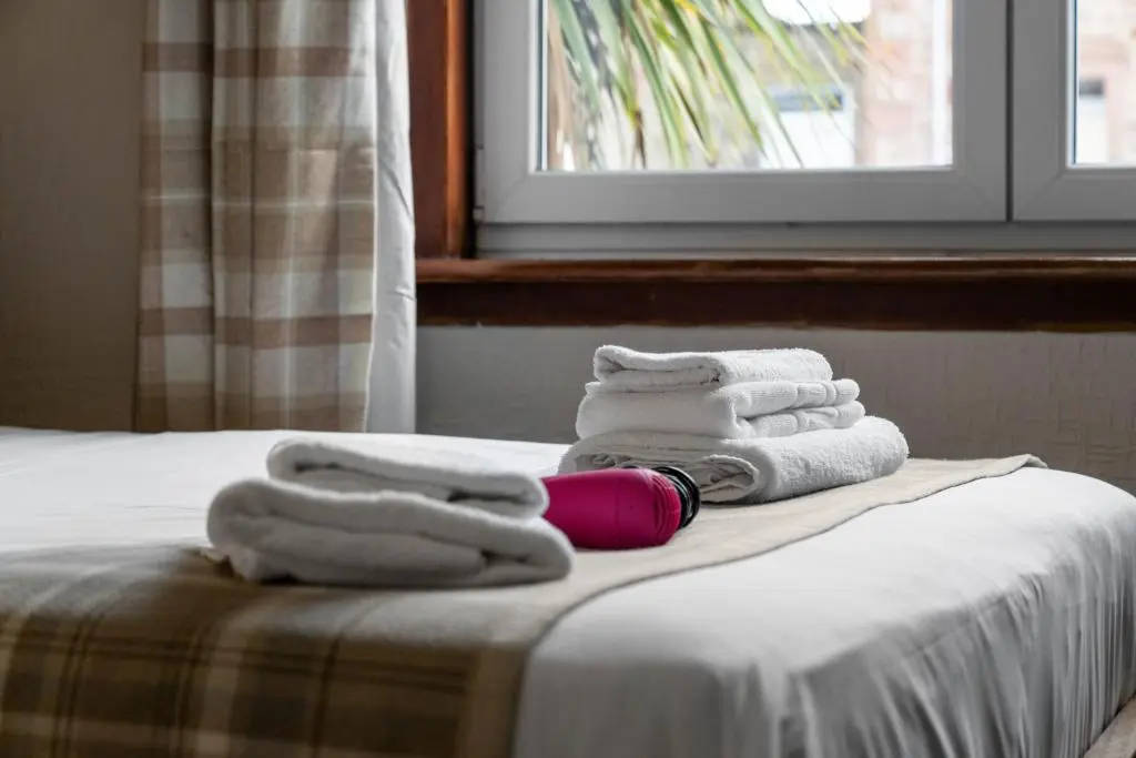 a pile of towels sitting on top of a bed at mySTAYINN Strathblane 7 Bedroom Full House - Inverness in Inverness