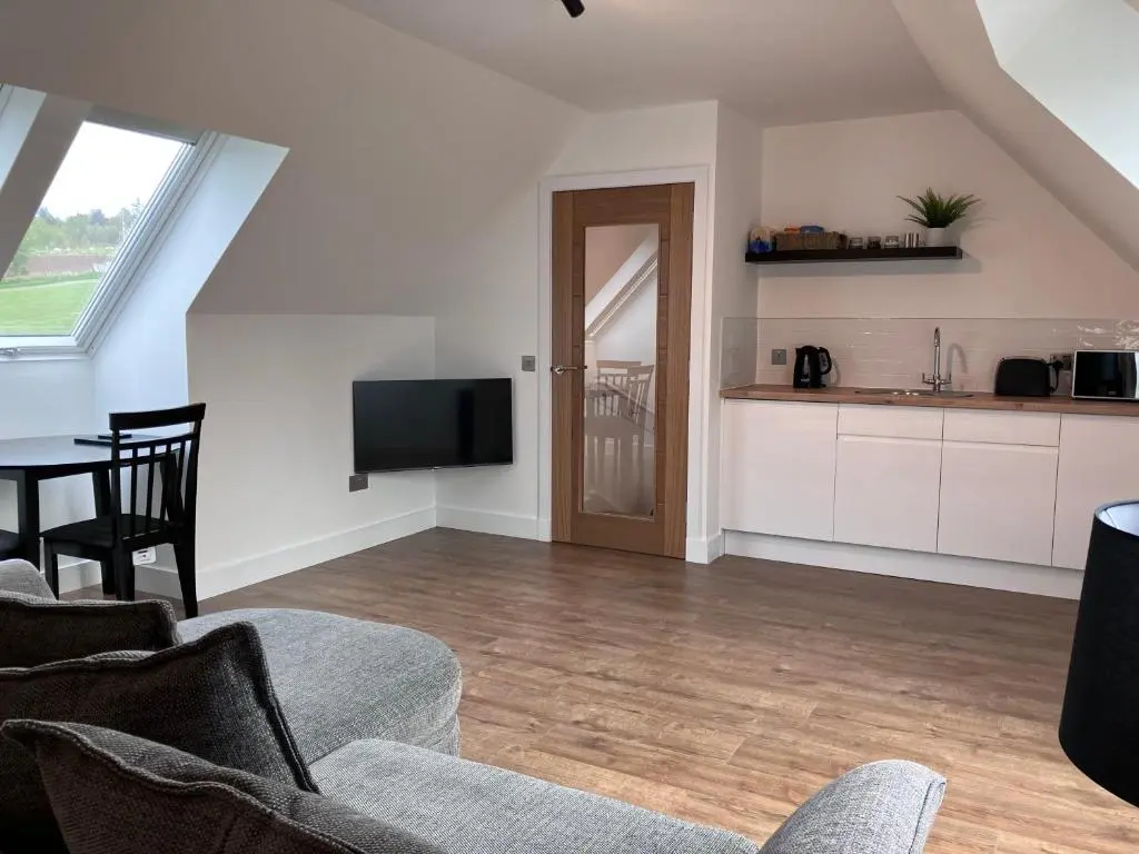 a living room with a couch and a tv and a table at Berryfield Holiday Apartment in Inverness