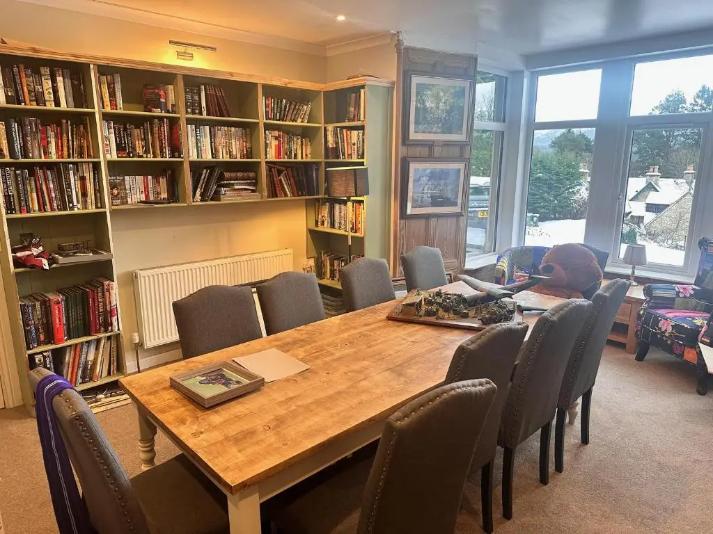 a man sitting at a table in a library at Forces Manor in Kincraig