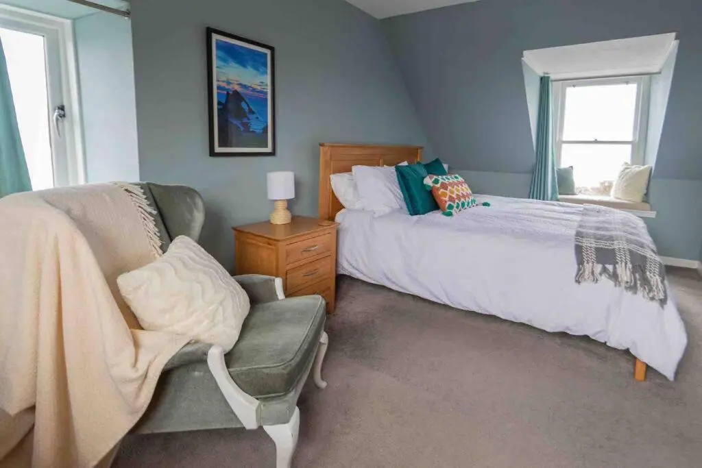 a bedroom with a bed and a chair and a window at Hill Crest - Clifftop Escape with Sea View in Cullen