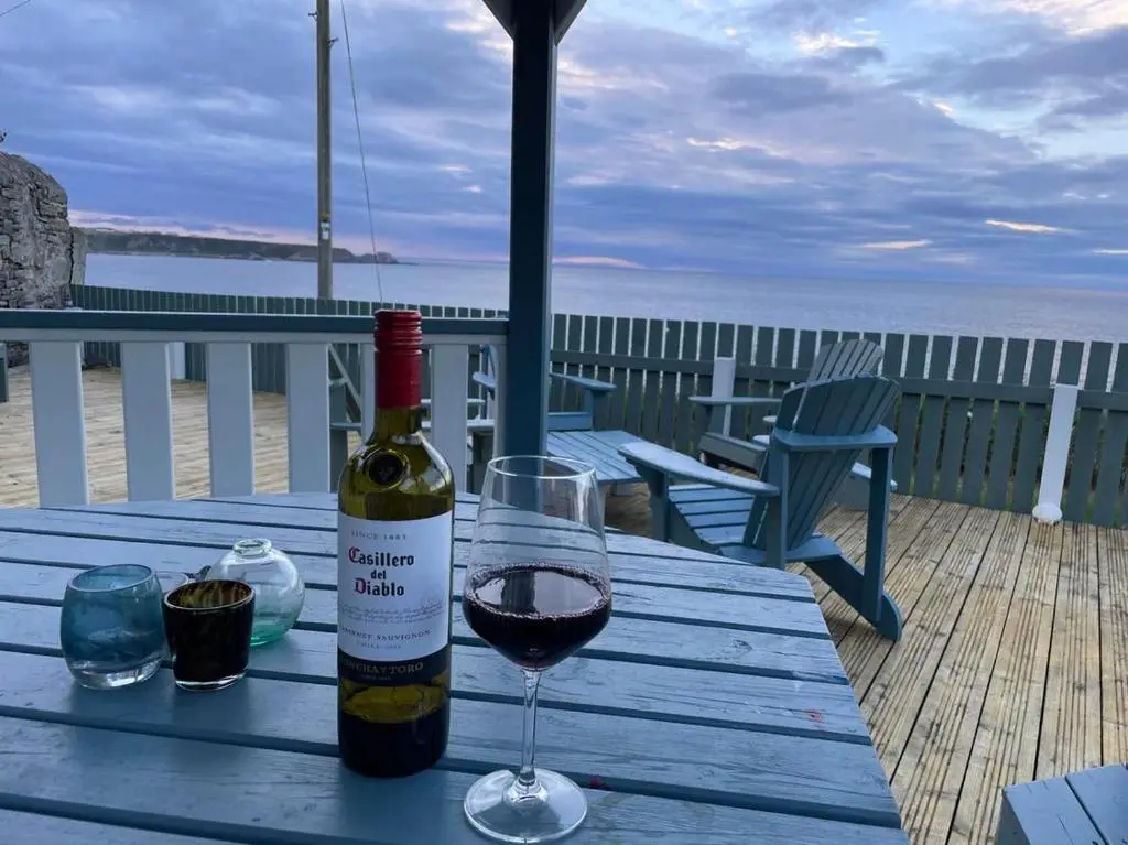 a bottle of wine sitting on a table with a glass at Hill Crest - Clifftop Escape with Sea View in Cullen