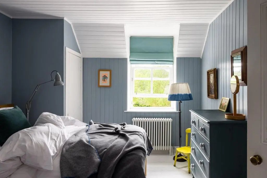 a blue bedroom with a bed and a window at Cuttieshillock in Banchory